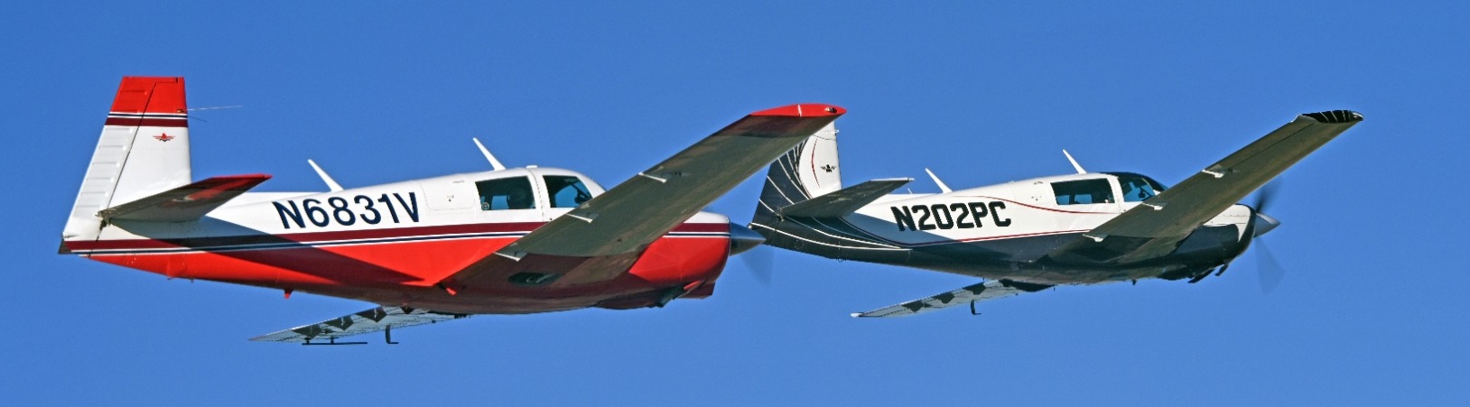 Two Mooneys flying in formation, with both aircraft visible